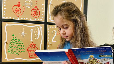 kleines Mädchen schaut sich das Buch aus dem Adventskalender an