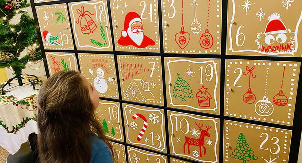 kleines Mädchen sucht die richtige Zahl auf dem XXL-Adventskalender