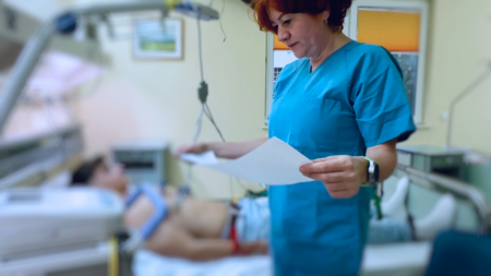 Ärztin sieht sich EKG-Ausdruck an; Patient auf Liege