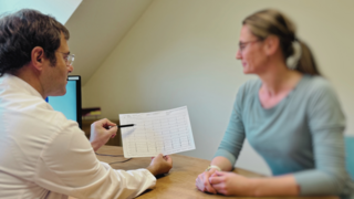 Arzt wertet mit Patientin EKG-Ausdruck aus