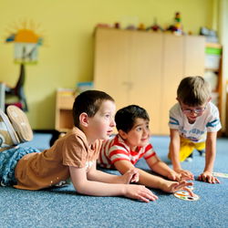 Kinder liegen auf dem Boden und spielen Kartenspiel