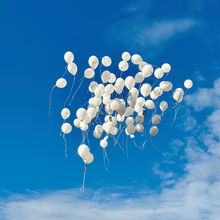 weiße Luftballons steigen in den Himmel