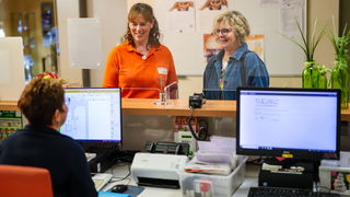 zwei Personen stehen an Rezeption