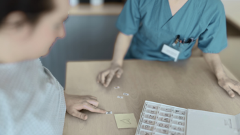 medizinische Fachkraft hilft Patientin beim sortieren von Buchstaben