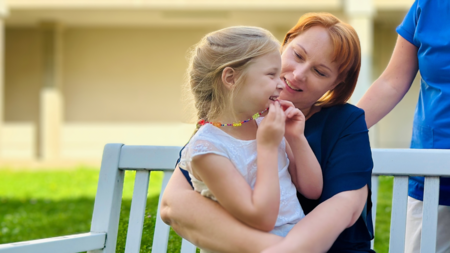 Frau hat lachendes Kind auf Schoß