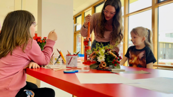 Kinder sitzen an einem Tisch und malen