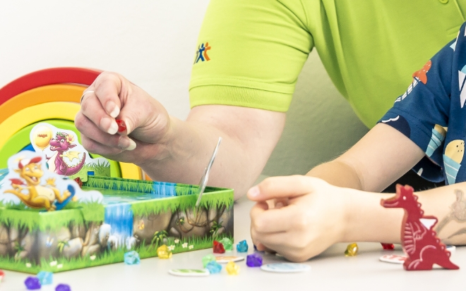 Kind platziert Dinosaurier-Figuren auf einem Spielbrett