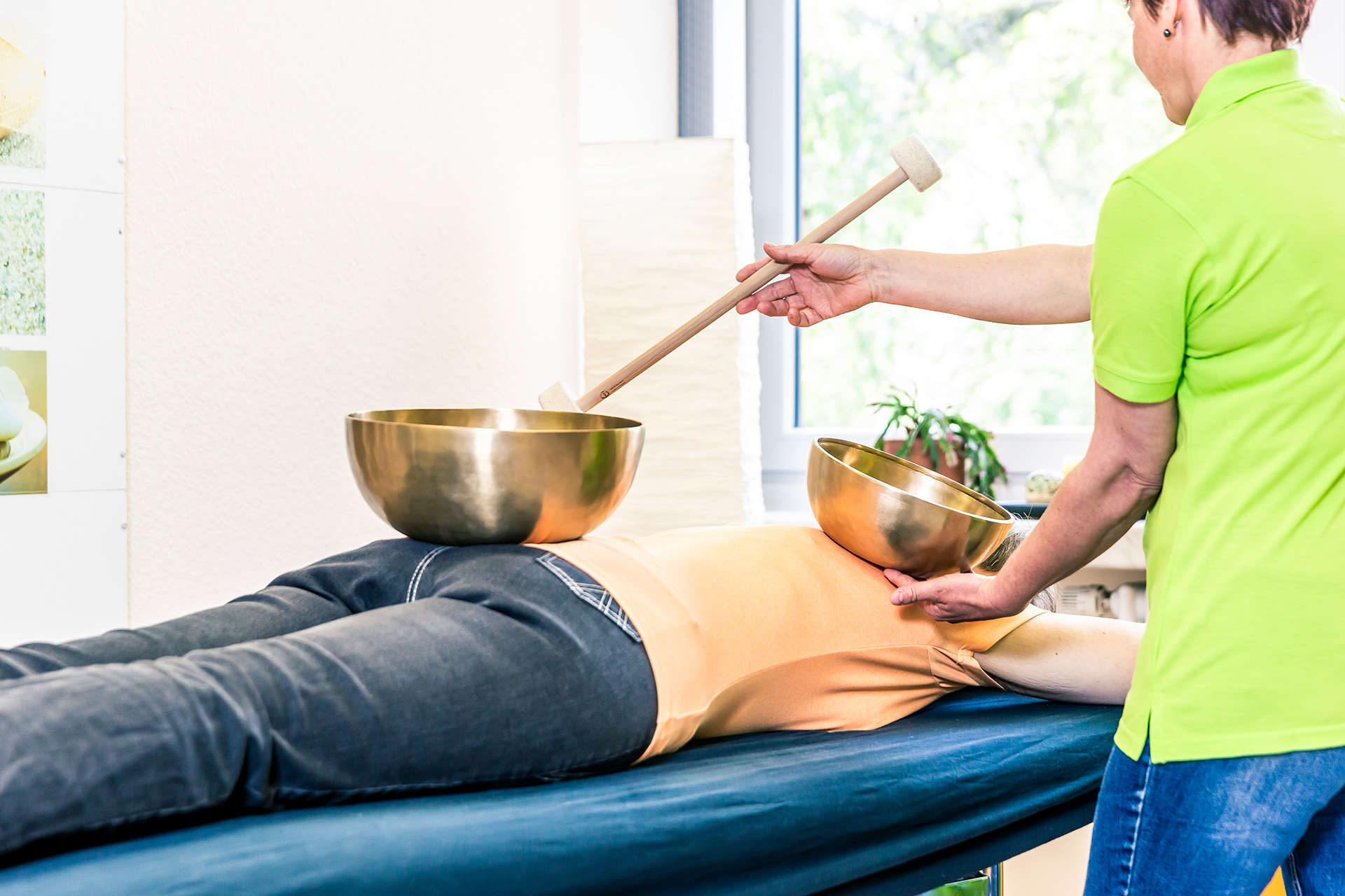 Klangschalentherapie: Patientin liegt auf Bauch, auf ihrem Rücken stehen die Klangschalen