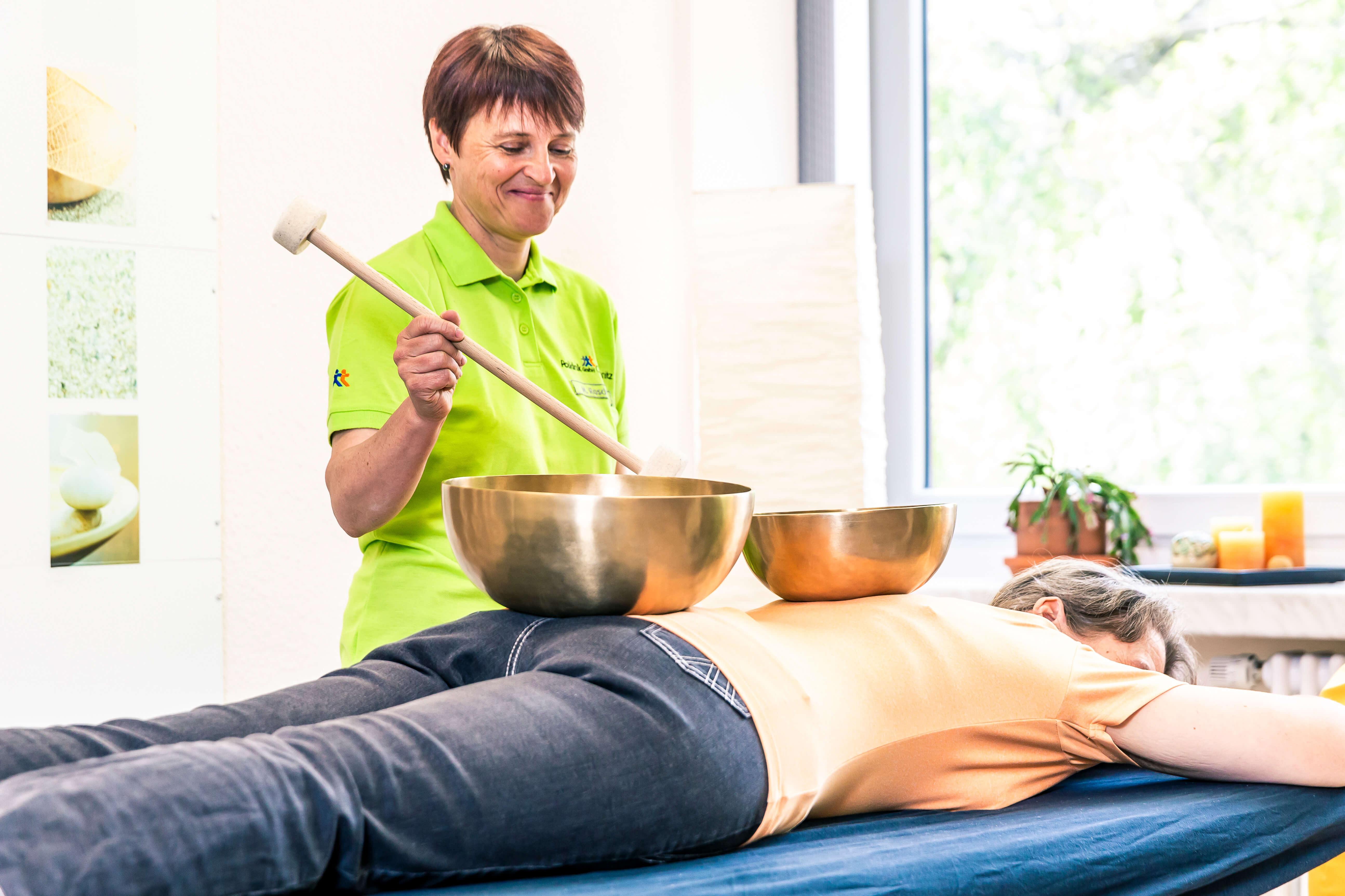 Klangschalentherapie: Patientin liegt auf Bauch, auf ihrem Rücken stehen die Klangschalen